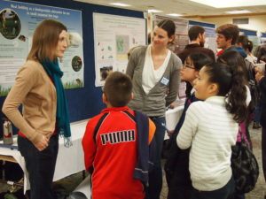 Elementary students investigating posters with GDPE graduate student