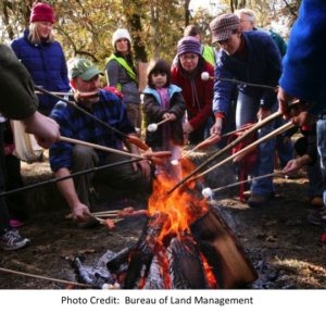 Group roasting marshmallows on a fire.